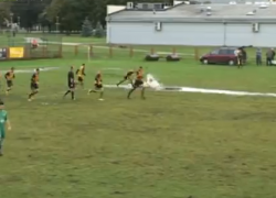 Un partido de fútbol sobre una mezcla de charcos y barro