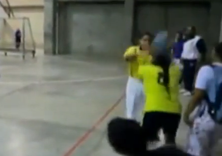 Un árbitro de fútbol-sala, a la carrera delante de una jugadora Un árbitro de fútbol-sala, a la carrera delante de una jugadora
